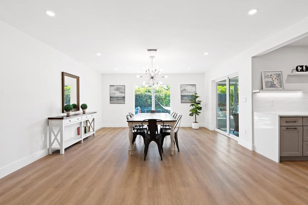 A dining room features light wood flooring, a modern chandelier, and a white sideboard — 486 NE 29th Street, Boca Raton FL 33431, BOCA RATON, FL