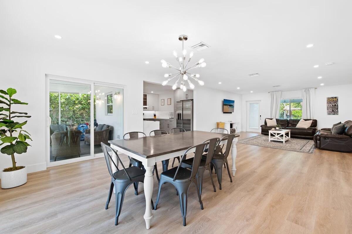 An open-concept dining and living area features light wood floors, white walls, and modern lighting — 486 NE 29th Street, Boca Raton FL 33431, BOCA RATON, FL