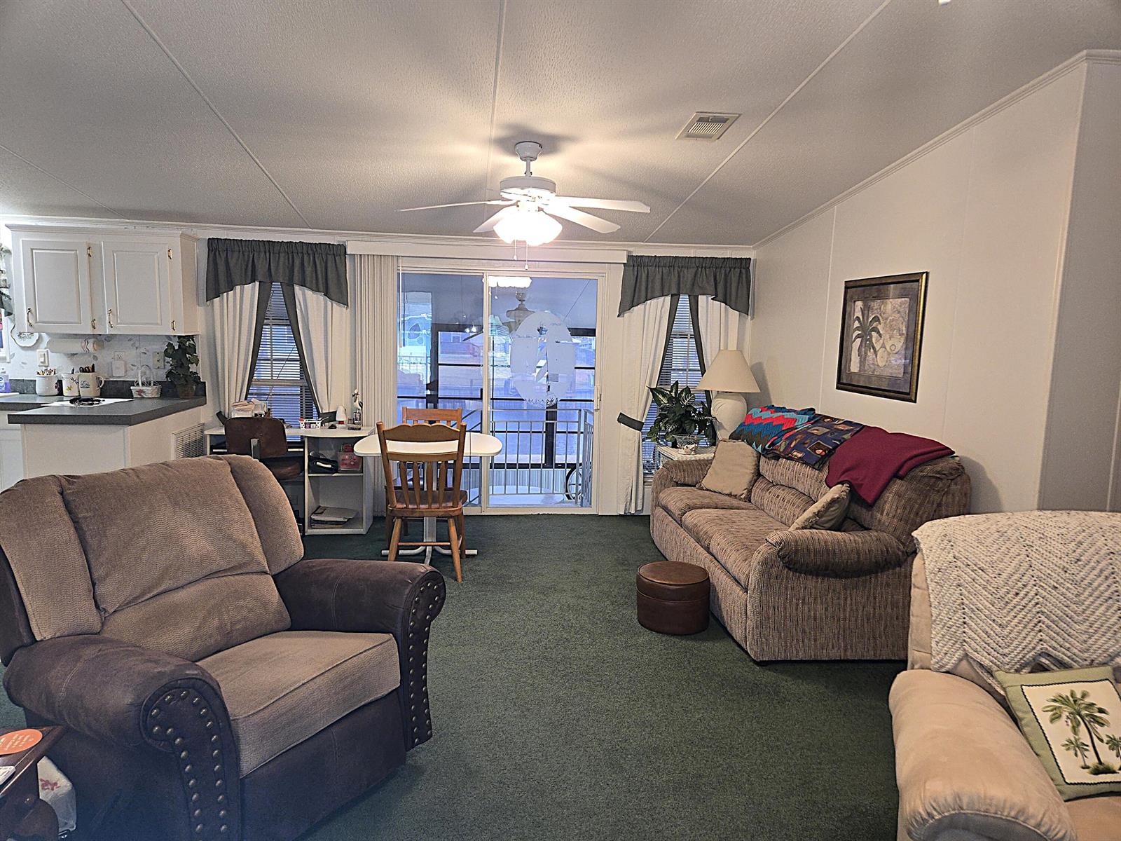 A living room with green carpet, a sofa, armchairs, and a sliding glass door — 2425 SE 31st Street, Okeechobee FL 34974, OKEECHOBEE, FL