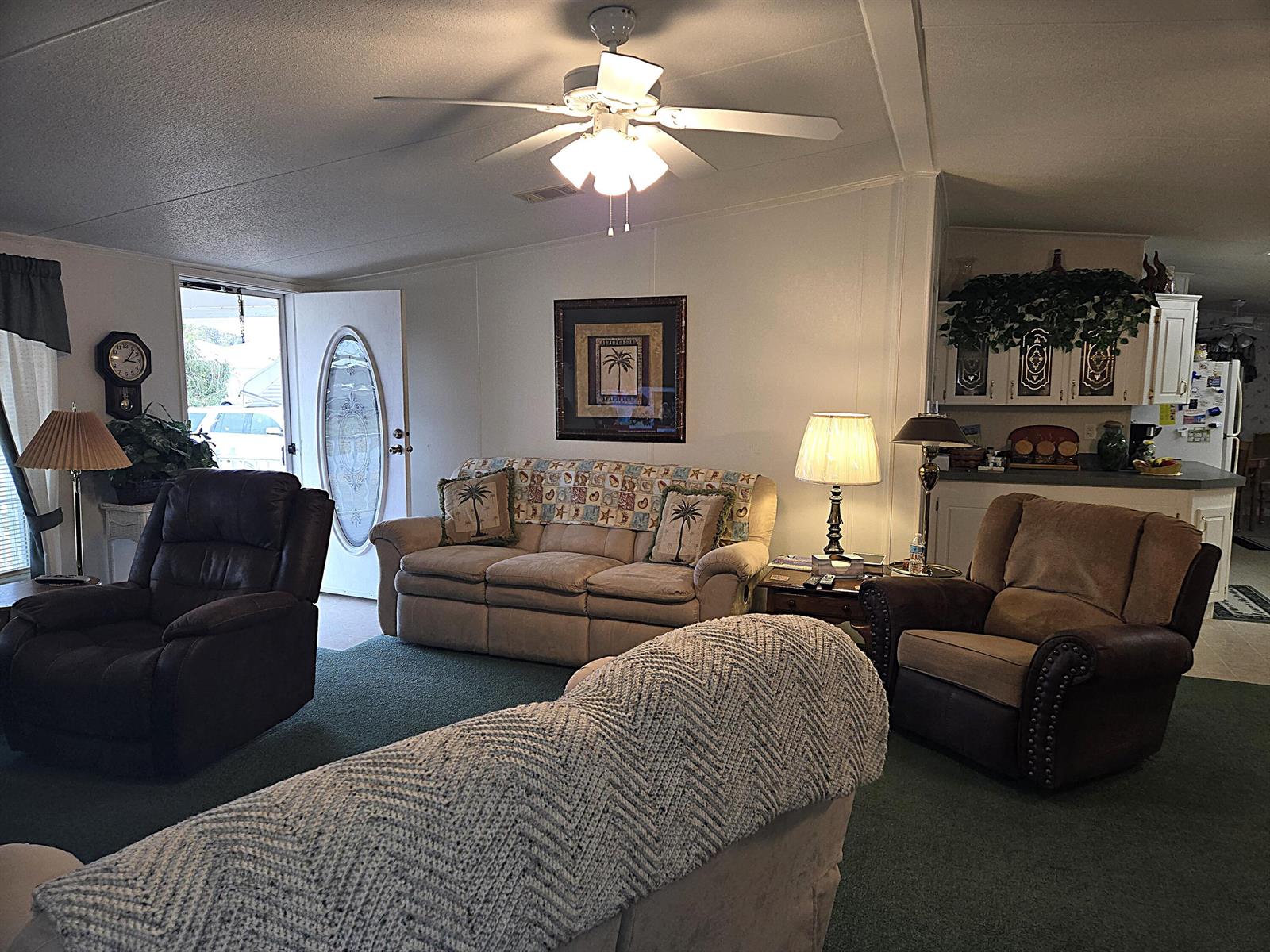 A living room features a sofa, two armchairs, a ceiling fan, and a kitchen area — 2425 SE 31st Street, Okeechobee FL 34974, OKEECHOBEE, FL