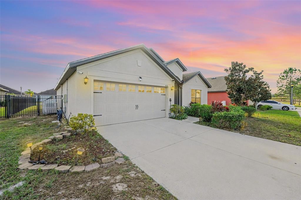 A single-story house with a two-car garage and a concrete driveway at sunset — 5630 ELSINORE WAY, LAKELAND, FL
