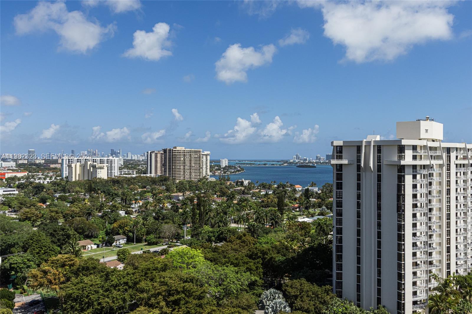 An elevated view shows a residential neighborhood, a bay, and high-rise buildings under a blue sky — 2000 Towerside Ter, Miami FL 33138, MIAMI, FL
