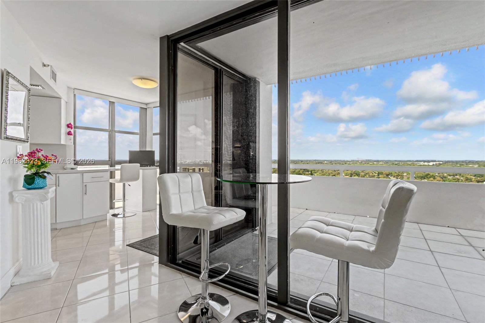 A bright room with white tile floors, a glass table, and a balcony with views — 2000 Towerside Ter, Miami FL 33138, MIAMI, FL