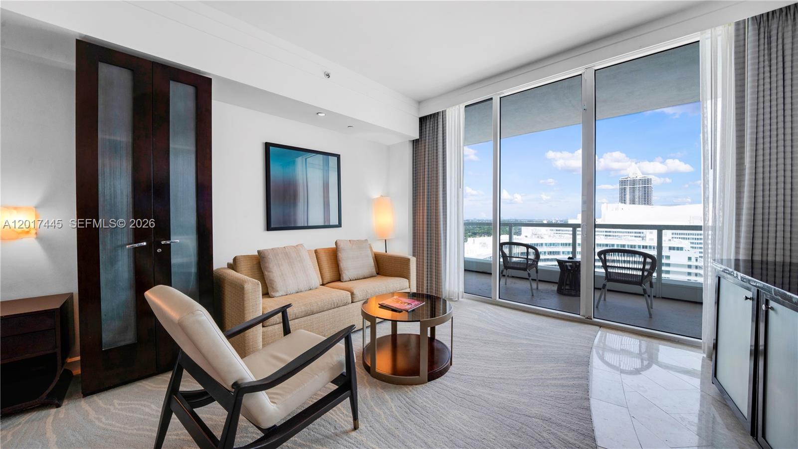 A living room features a beige sofa, an armchair, a coffee table, and a balcony view — 4391 Collins Ave # 1903, Miami Beach FL 33140, MIAMI BEACH, FL