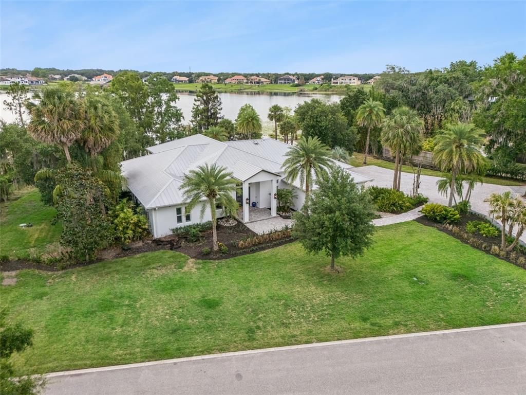 An aerial view shows a single-story house with a metal roof situated by a lake — 5624 W LAKE BUTLER ROAD, WINDERMERE, FL