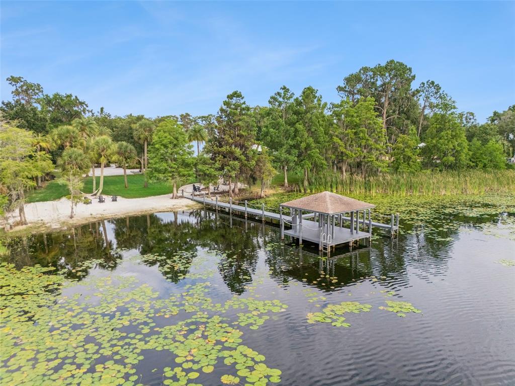 A wooden dock with a covered gazebo extends into a lake filled with lily pads — 5624 W LAKE BUTLER ROAD, WINDERMERE, FL