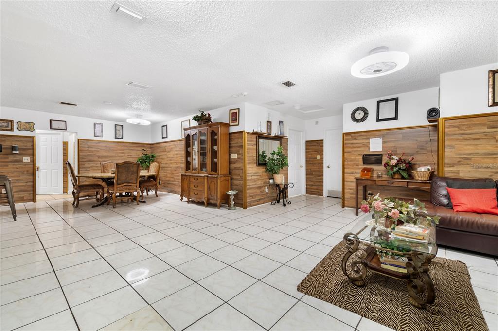 A spacious living and dining area features white tile floors and wood-paneled walls — 613 FOREST HILLS DRIVE, BRANDON, FL