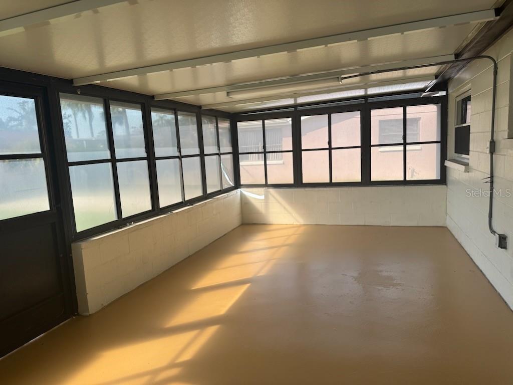 A sunroom with a painted concrete floor, white block walls, and many window panels — 9617 LAKE CHRISE LANE, PORT RICHEY, FL