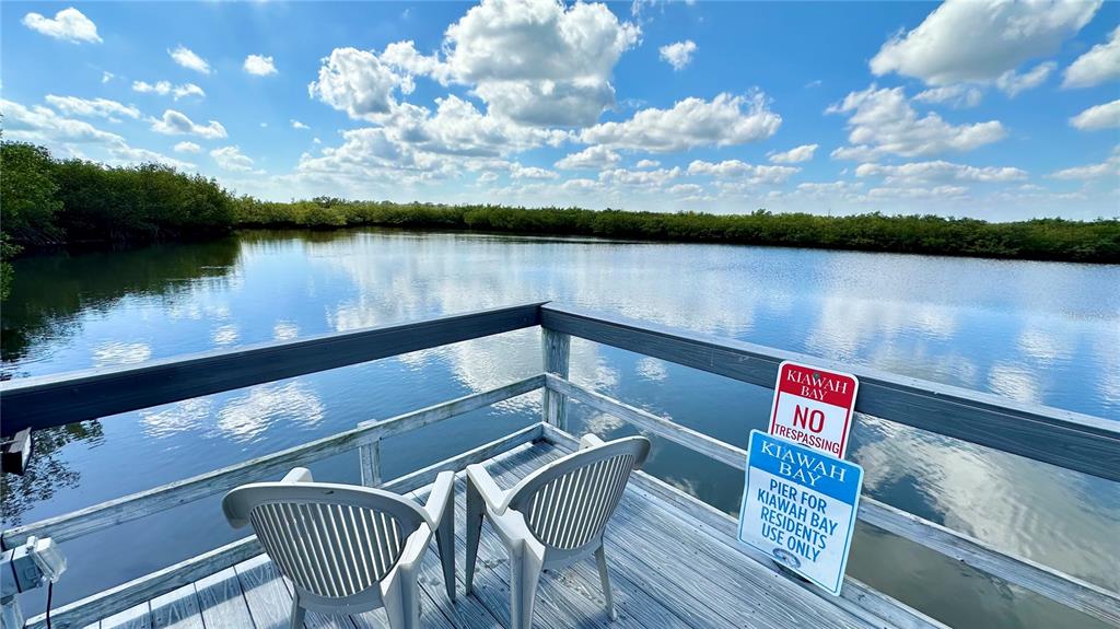 A wooden pier with two plastic chairs overlooks a calm body of water — 4860 S ATLANTIC AVENUE UNIT 1030, NEW SMYRNA BEACH, FL