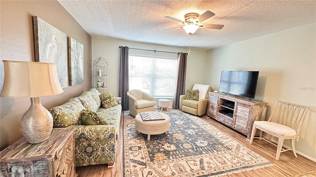 A living room features a patterned sofa, a central ottoman, and a television on a console — 4860 S ATLANTIC AVENUE UNIT 1030, NEW SMYRNA BEACH, FL