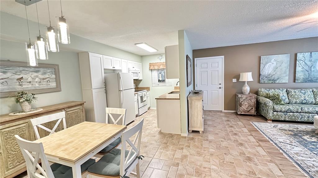 An open-concept kitchen and dining area features white cabinetry, tile flooring, and a living space — 4860 S ATLANTIC AVENUE UNIT 1030, NEW SMYRNA BEACH, FL
