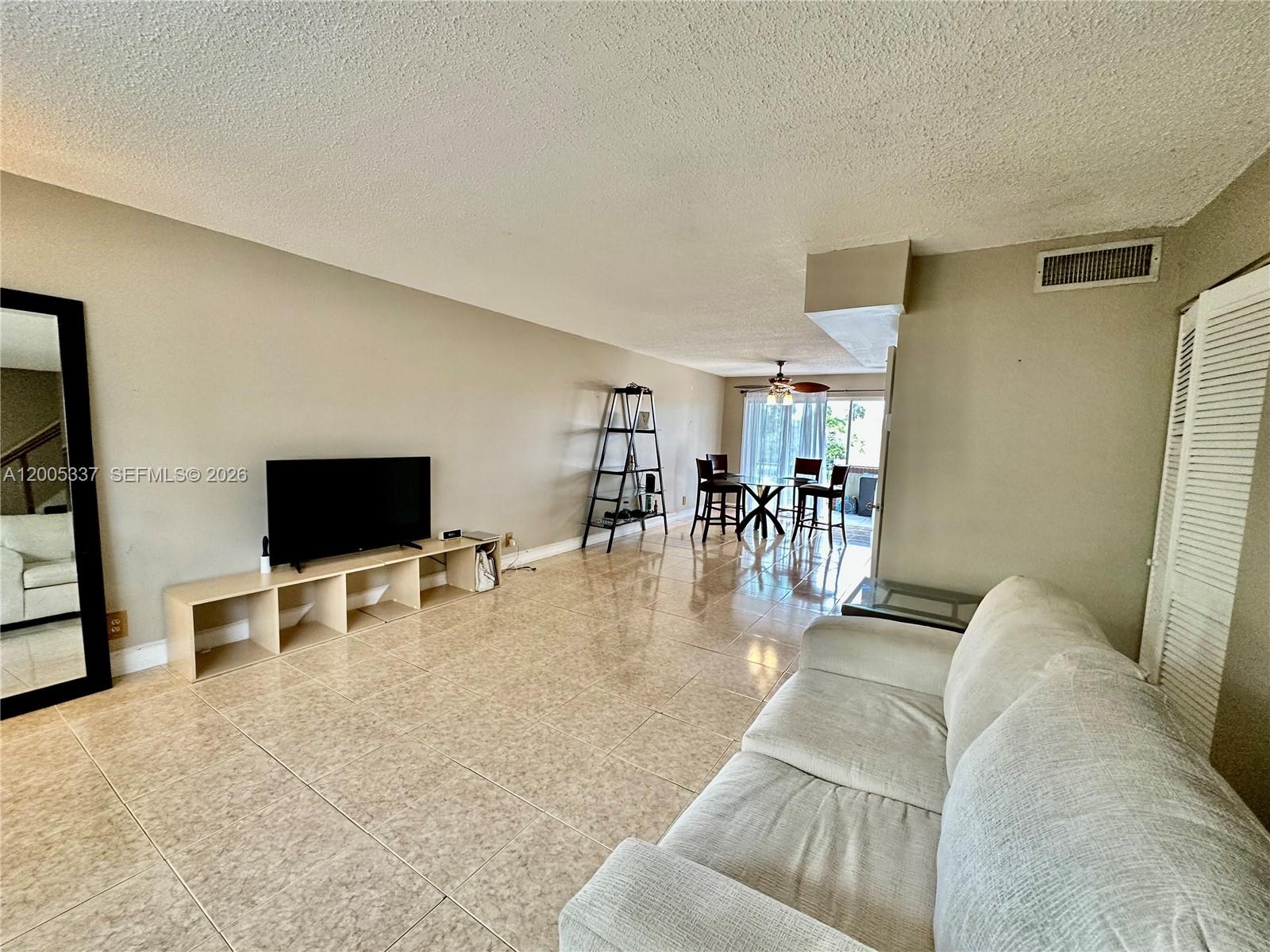 A living room features beige tile flooring, a television console, and a dining area — 1100 SE 4th Ave # 32, Deerfield Beach FL 33441, DEERFIELD BEACH, FL