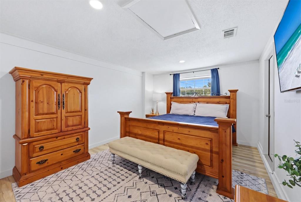 A bedroom features a wooden bed frame, a matching armoire, and a beige tufted bench — 1730 BLUE BIRD LANE, ENGLEWOOD, FL