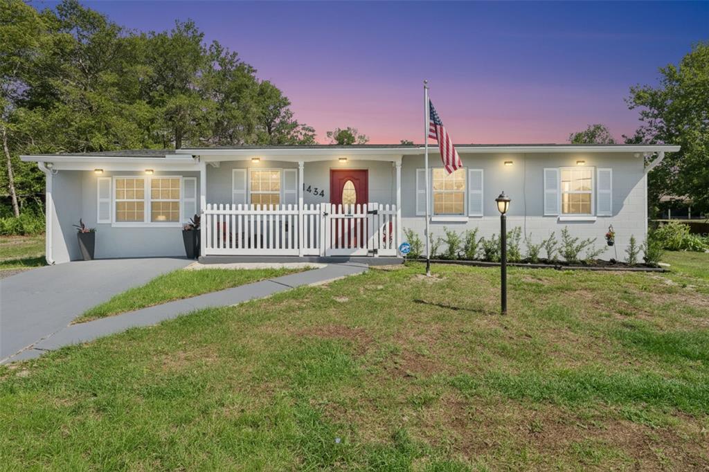 A single-story house with a white exterior, red front door, and a white picket fence — 1434 DELTONA BOULEVARD, DELTONA, FL