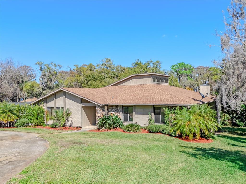 A single-story house with a brown shingled roof, stone accents, and a prominent central clerestory — 2918 COCOVIA WAY, LEESBURG, FL