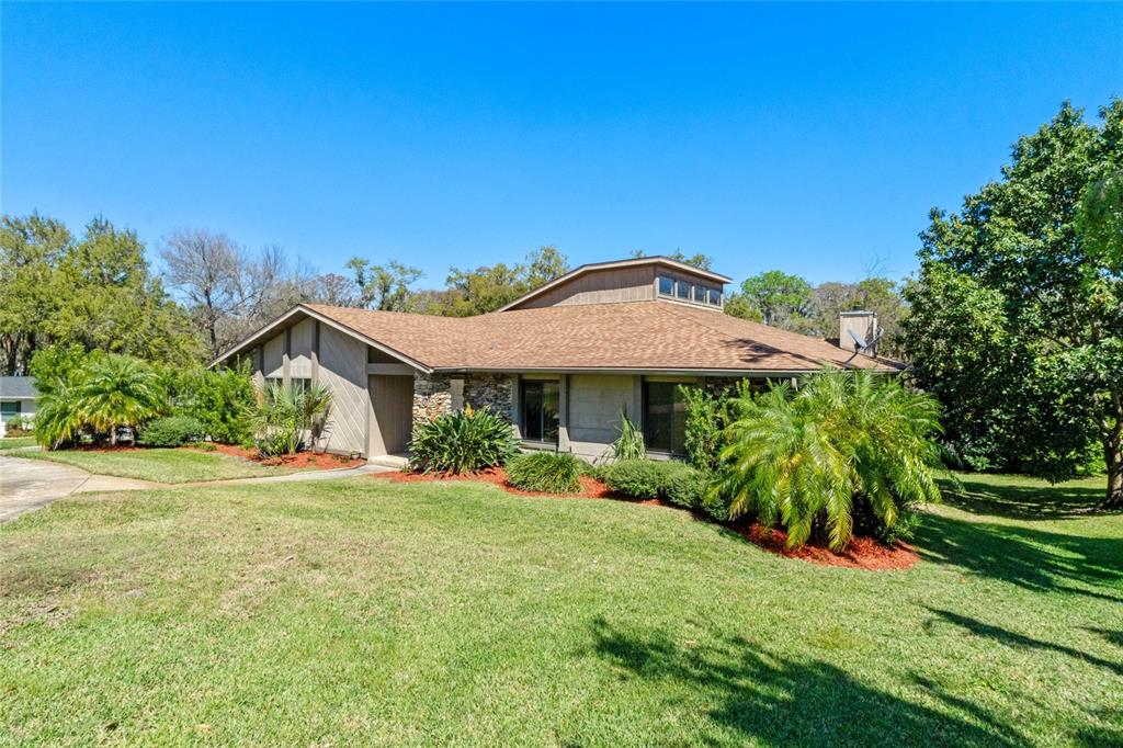 A single-story house with a brown shingled roof, stone accents, and a raised clerestory section — 2918 COCOVIA WAY, LEESBURG, FL