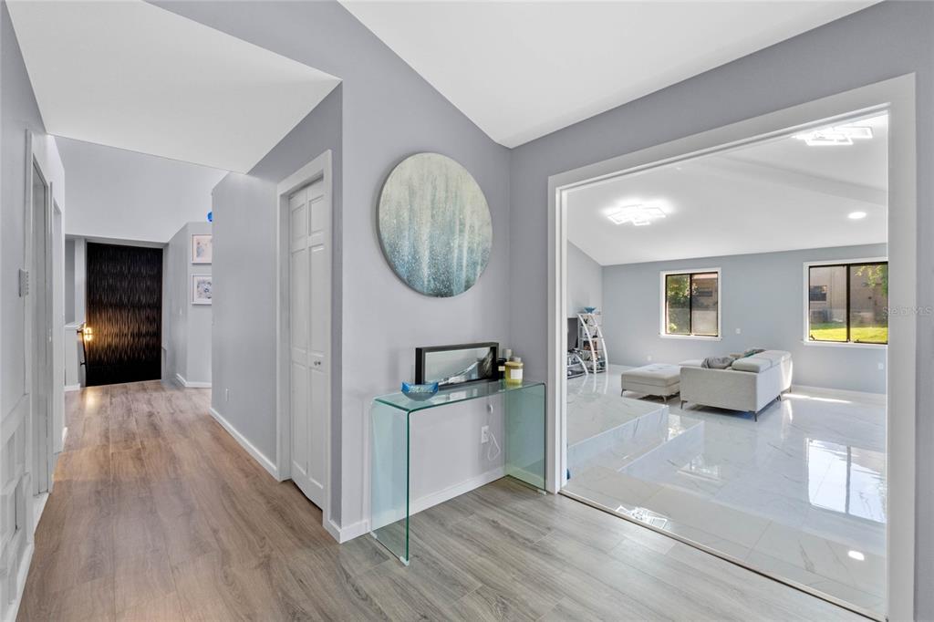 An entryway with wood-look flooring leads to a sunken living room with white tile floors — 2918 COCOVIA WAY, LEESBURG, FL