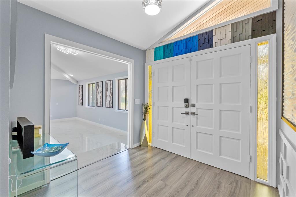 An entryway features a white double door, wood-look flooring, and a decorative blue-to-grey wall accent — 2918 COCOVIA WAY, LEESBURG, FL