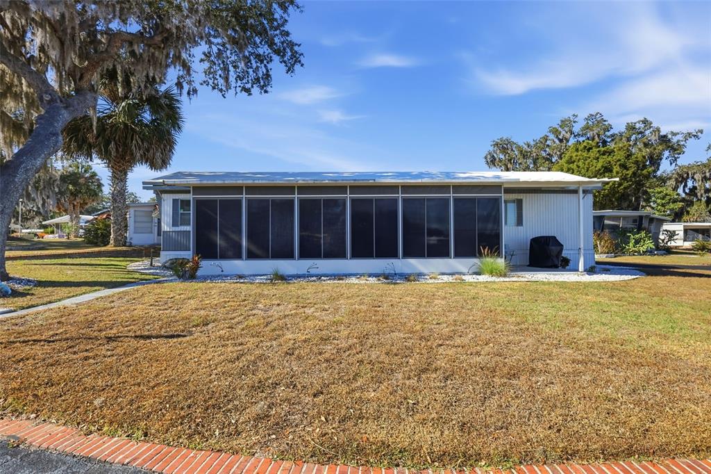 A single-story manufactured home features a large screened-in porch and a dry, grassy yard — 3896 PICCIOLA ROAD UNIT #371, FRUITLAND PARK, FL