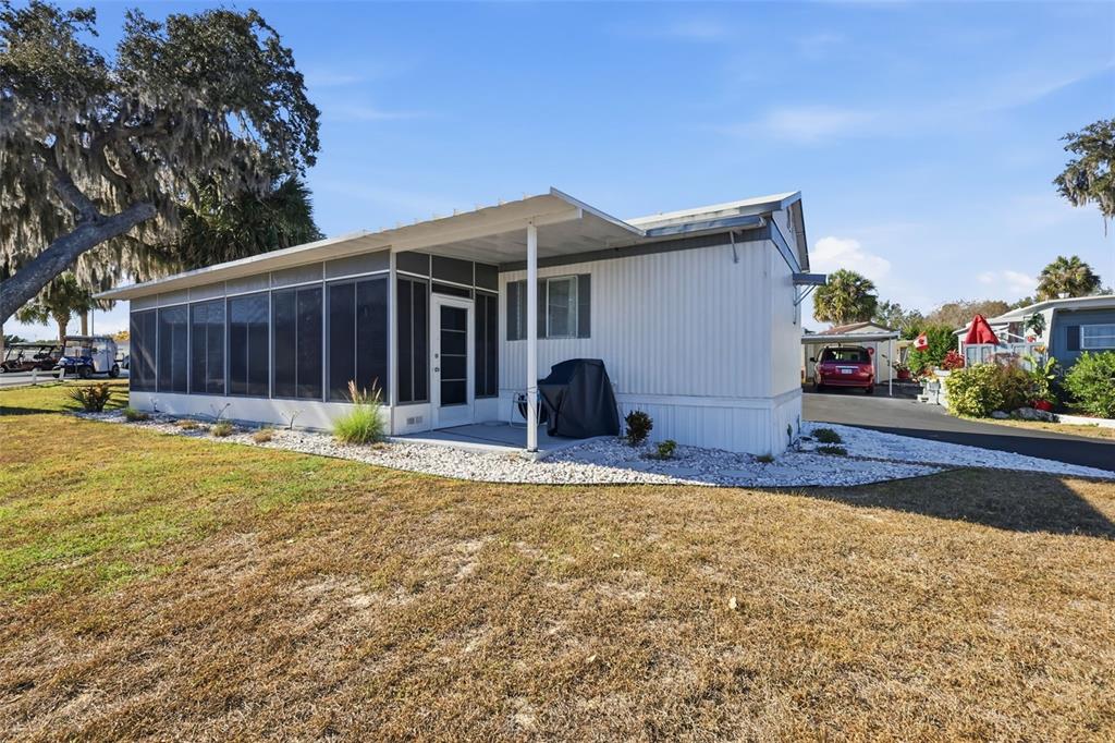 A white mobile home with a screened-in porch and a gravel landscaping border — 3896 PICCIOLA ROAD UNIT #371, FRUITLAND PARK, FL