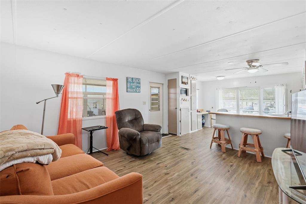 A living room with wood-look flooring, an orange sofa, a recliner, and a breakfast bar — 3896 PICCIOLA ROAD UNIT #371, FRUITLAND PARK, FL