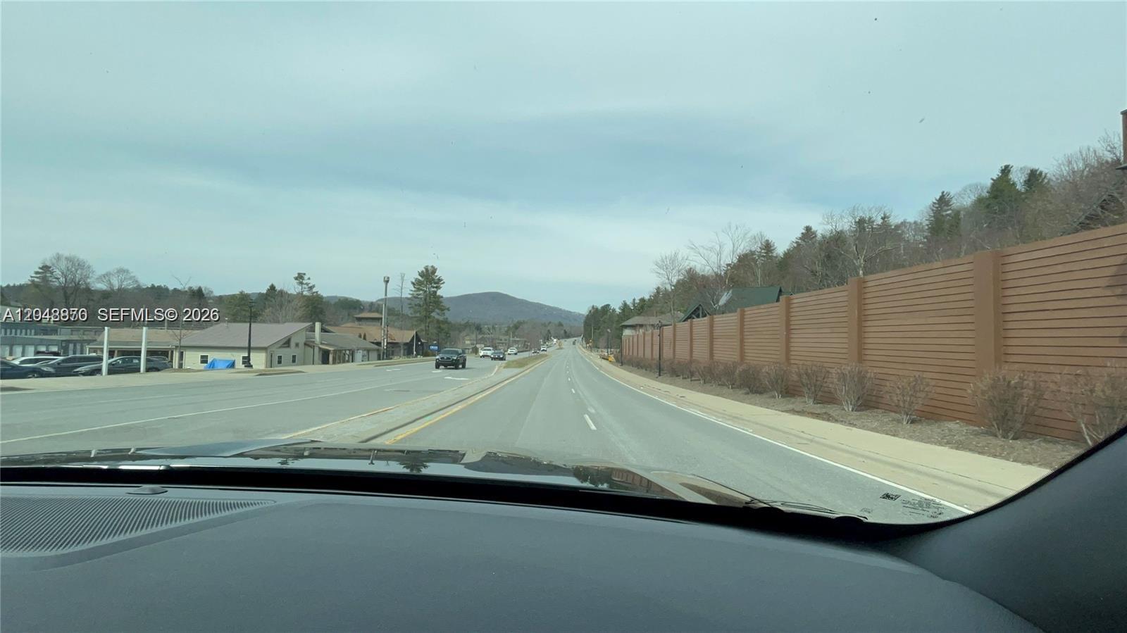A view from inside a vehicle driving down a road lined with a wooden fence — Great Sky Dr, NC, NC
