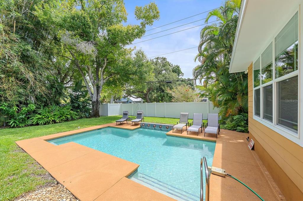 A backyard swimming pool with a tan deck, lounge chairs, and a white privacy fence — 2395 HYDE PARK STREET, SARASOTA, FL