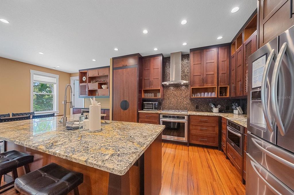 A kitchen features dark wood cabinets, granite countertops, a large island, and stainless steel appliances — 2395 HYDE PARK STREET, SARASOTA, FL