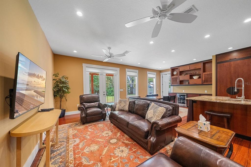 A living room with a leather sofa, two armchairs, a television, and an open kitchen — 2395 HYDE PARK STREET, SARASOTA, FL