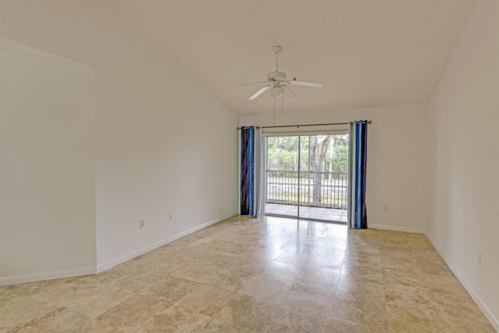An empty room with light-colored tile flooring, a ceiling fan, and sliding glass balcony doors — 3131 Clint Moore Road # 208, Boca Raton FL 33496, BOCA RATON, FL