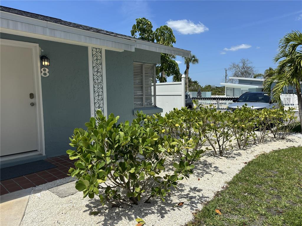 A light blue house exterior features a white door, decorative trim, and a gravel garden — 170 ROOSEVELT DRIVE UNIT 8, SARASOTA, FL