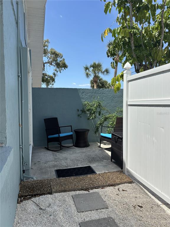 A small patio features two rocking chairs, a side table, and a white privacy fence — 170 ROOSEVELT DRIVE UNIT 8, SARASOTA, FL