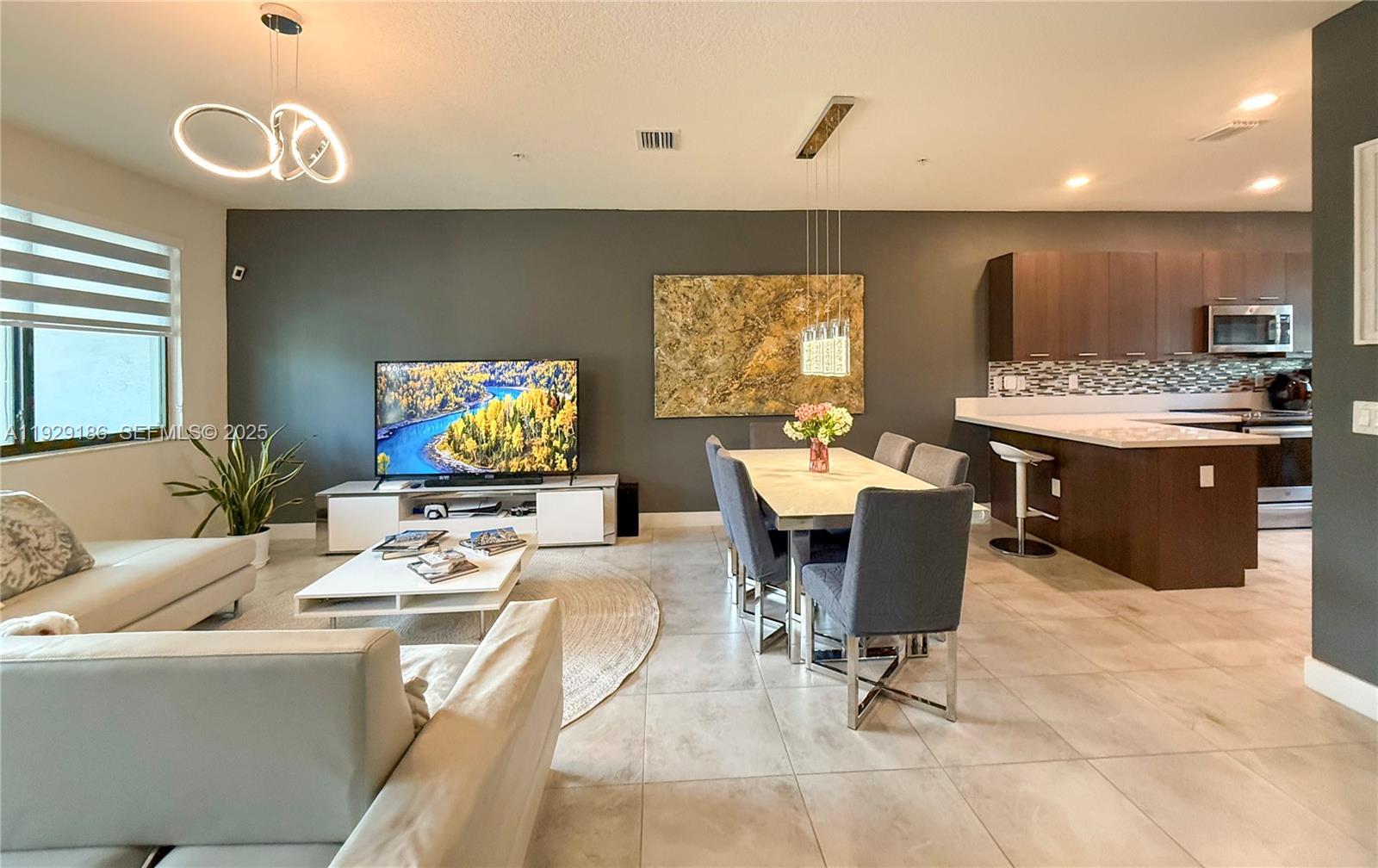 An open-concept living and dining area features dark gray walls, tile flooring, and modern furniture — 4654 NW 84th Ave, Doral FL 33166, DORAL, FL