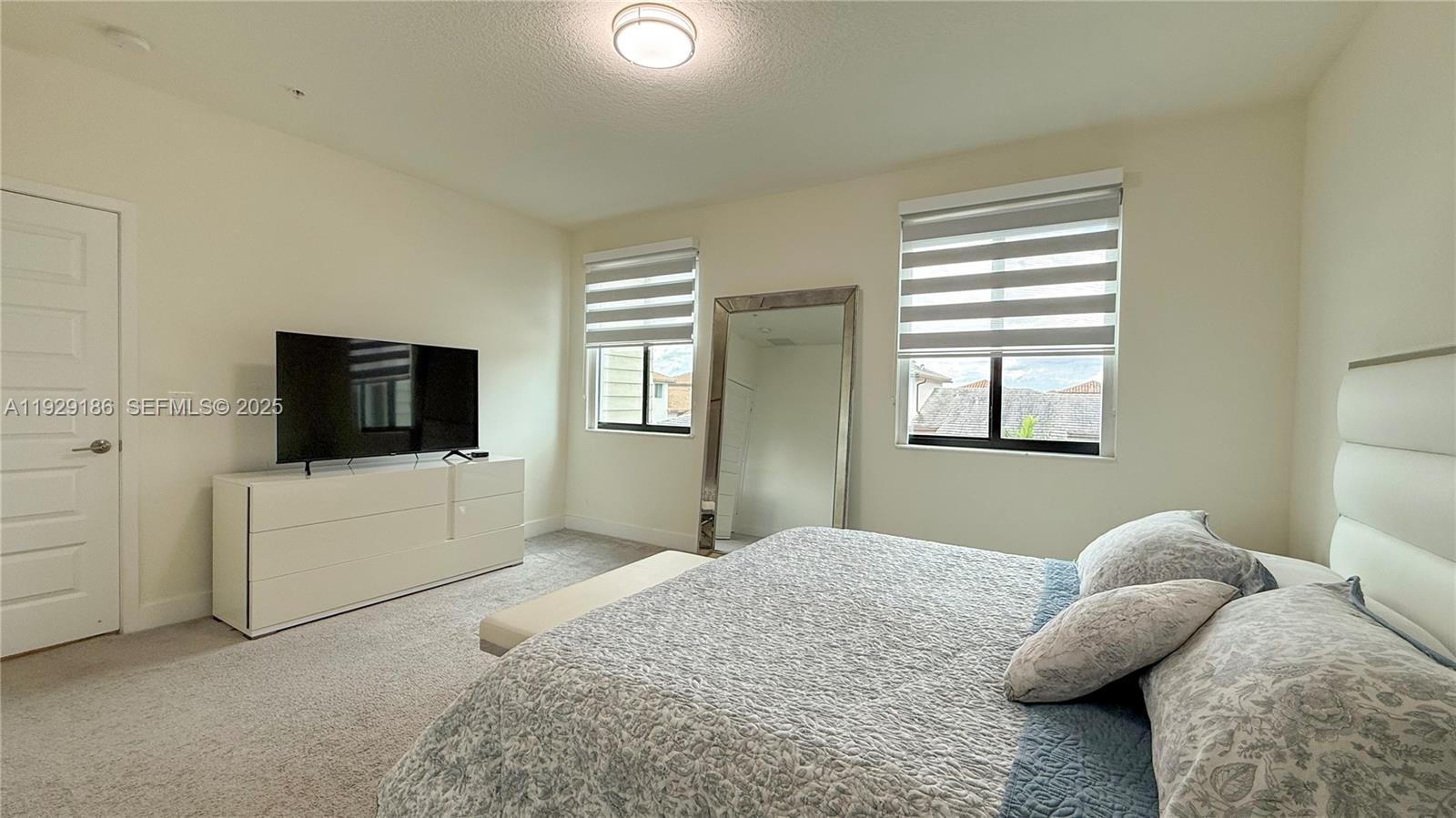 A bedroom features a bed, a dresser with a television, and a large floor mirror — 4654 NW 84th Ave, Doral FL 33166, DORAL, FL