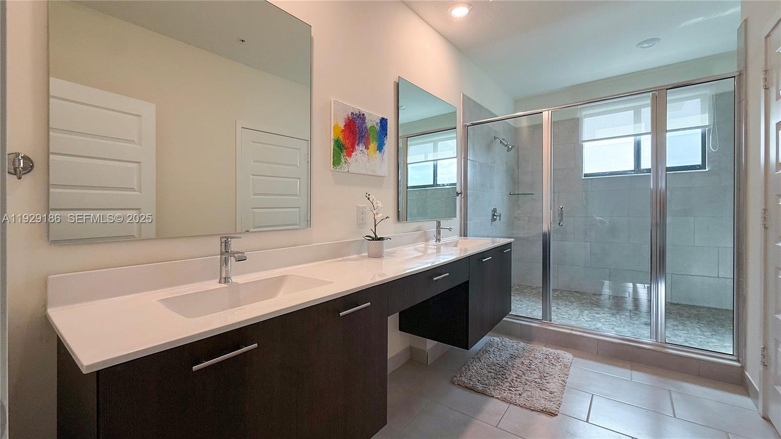 A modern bathroom features a double vanity with dark cabinets, white countertops, and a glass shower — 4654 NW 84th Ave, Doral FL 33166, DORAL, FL