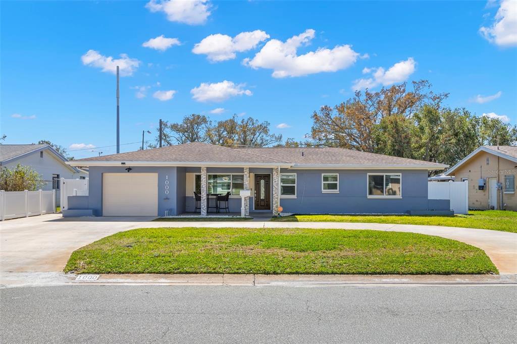 A single-story house with a blue exterior, a garage, and a front lawn — 1000 59TH AVENUE S, ST PETERSBURG, FL