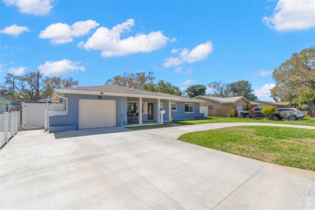 A blue single-story house features a concrete driveway, a garage, and a covered porch — 1000 59TH AVENUE S, ST PETERSBURG, FL