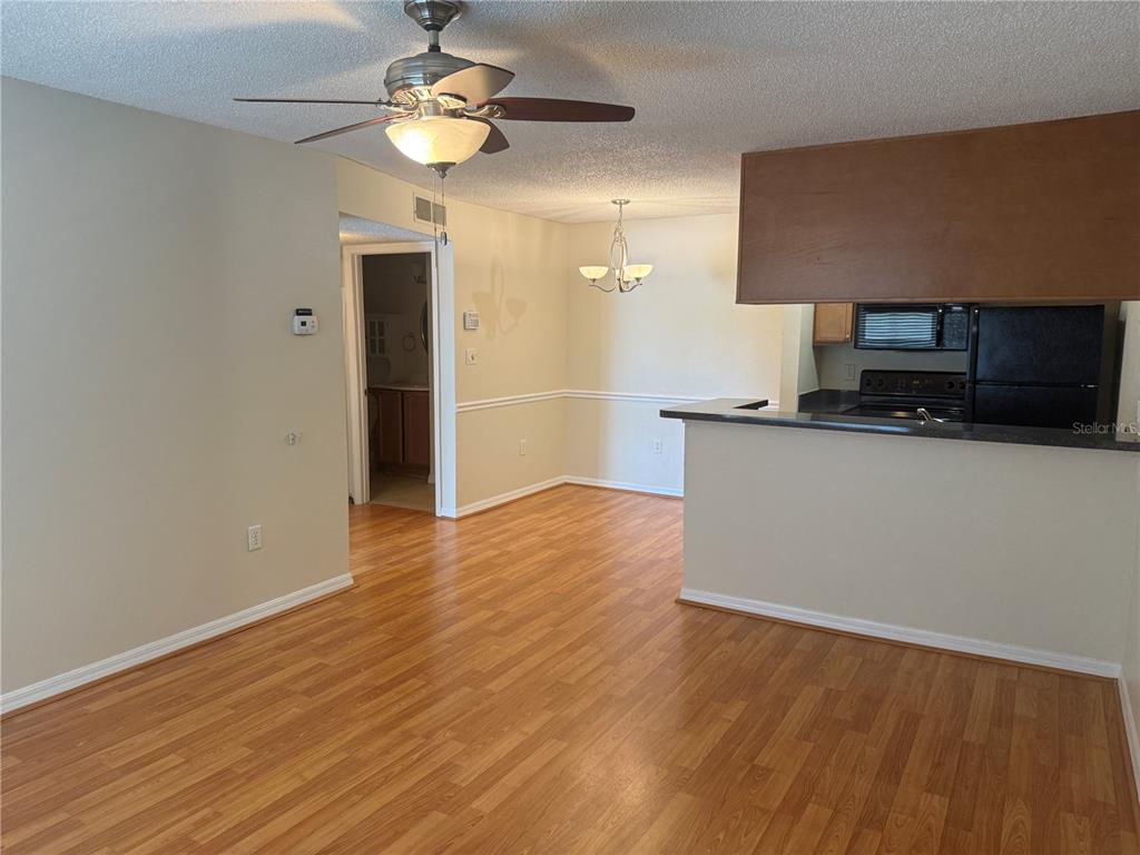 An open-concept living and dining area features wood-look flooring, a ceiling fan, and kitchen pass-through — 220 LAKE PARSONS GREEN UNIT 205, BRANDON, FL