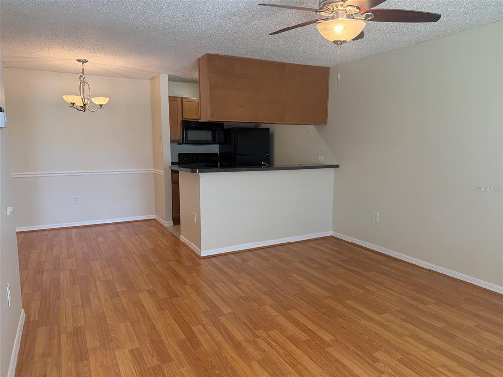 A living room and dining area with wood-look flooring, a ceiling fan, and kitchen pass-through — 220 LAKE PARSONS GREEN UNIT 205, BRANDON, FL