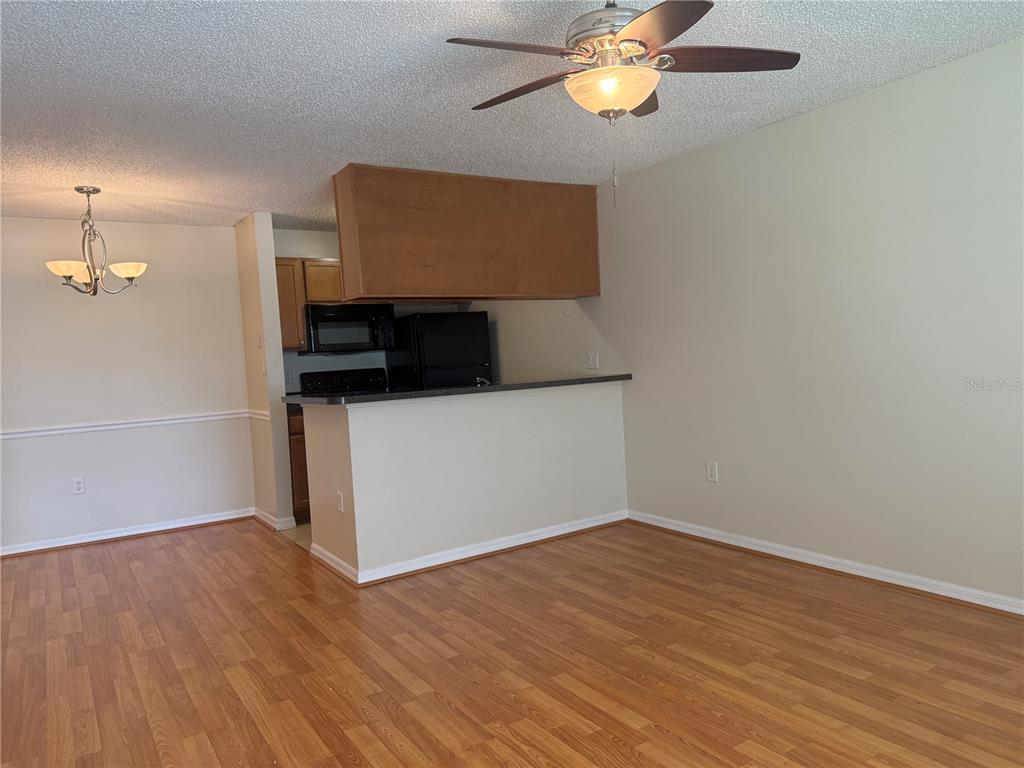 A living room with wood-look flooring features a breakfast bar opening into a kitchen — 220 LAKE PARSONS GREEN UNIT 205, BRANDON, FL
