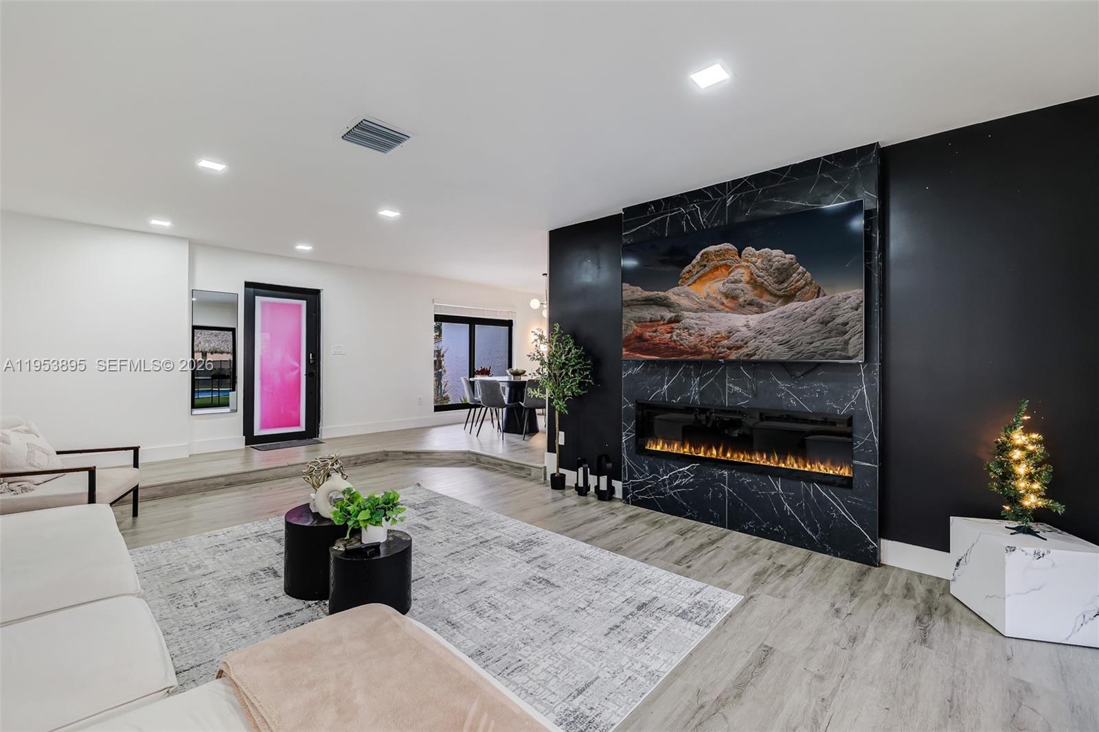 A living room features a black marble fireplace wall with an integrated television and fireplace — 10870 SW 106th Ave, Miami FL 33176, MIAMI, FL