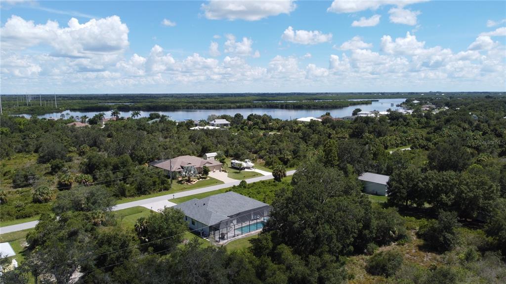 An aerial view shows two houses with pools and driveways surrounded by trees near water — Triple Lot TITUS TERRACE, PUNTA GORDA, FL