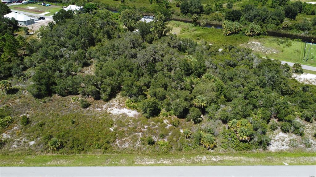 An aerial view shows a wooded, undeveloped residential lot bordered by a paved road — Triple Lot TITUS TERRACE, PUNTA GORDA, FL