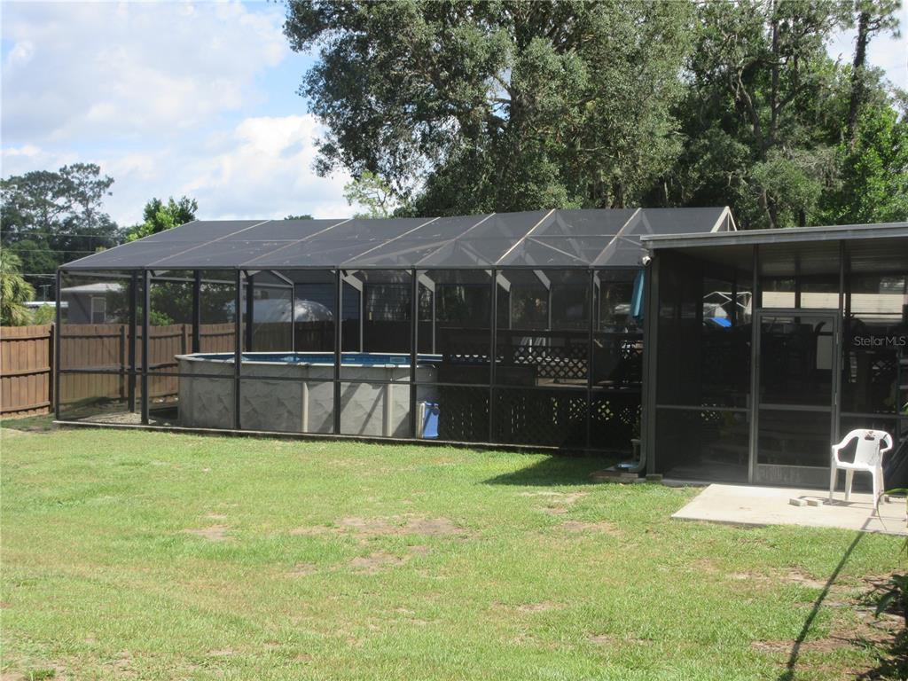 An above-ground swimming pool is enclosed within a large screened-in patio in a backyard — 2300 SE 173RD AVENUE, SILVER SPRINGS, FL