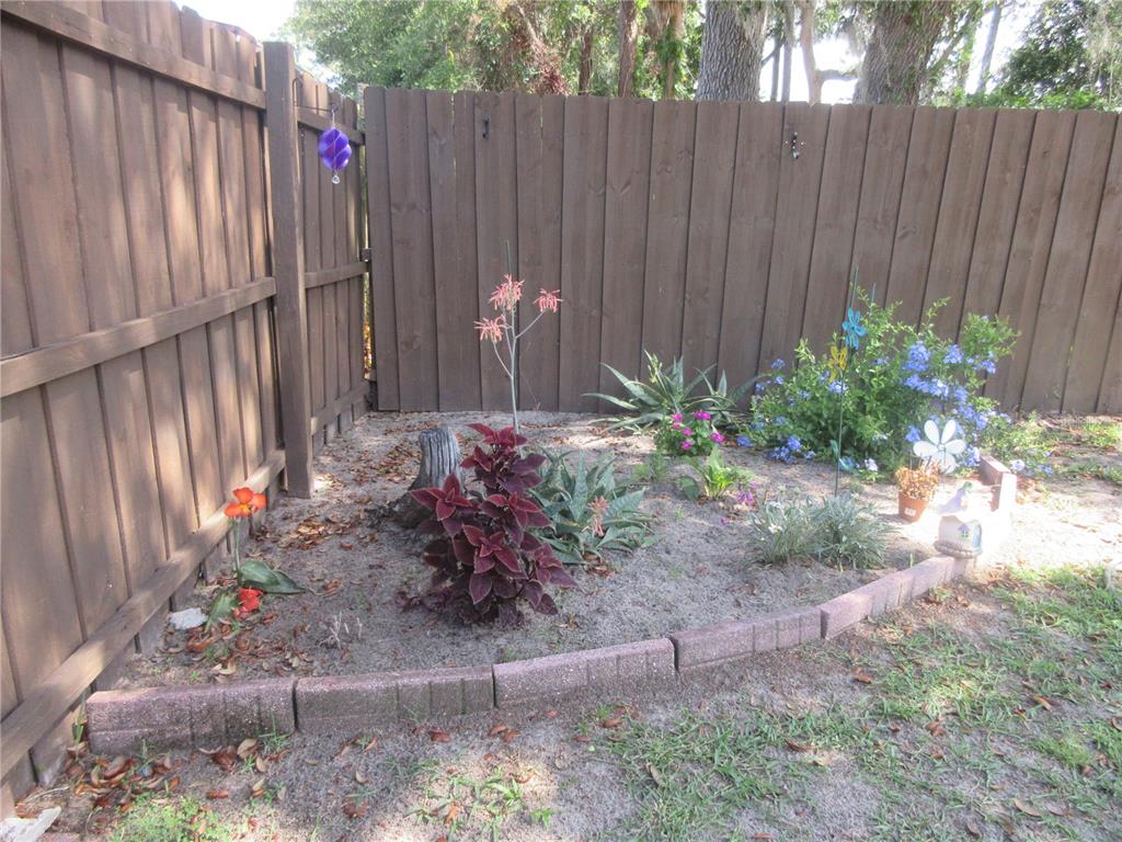 A small garden bed with various plants is enclosed by a curved brick border — 2300 SE 173RD AVENUE, SILVER SPRINGS, FL