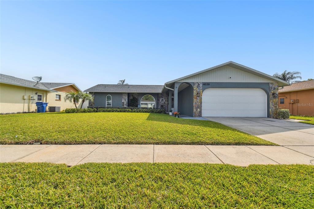 A single-story house with a gray exterior, stone accents, and a two-car garage — 4636 WHITETAIL LANE, NEW PORT RICHEY, FL