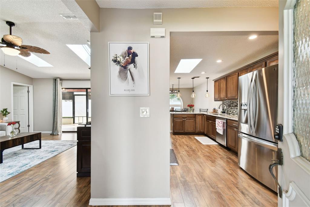 A view from an entryway looking into a kitchen and living area with wood flooring — 4636 WHITETAIL LANE, NEW PORT RICHEY, FL