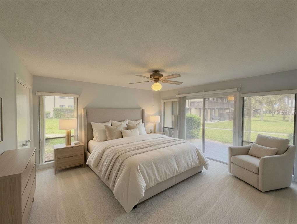 A bedroom features a king-sized bed, a beige armchair, and sliding glass doors to outside — 56 CLUB HOUSE DRIVE UNIT 101, PALM COAST, FL