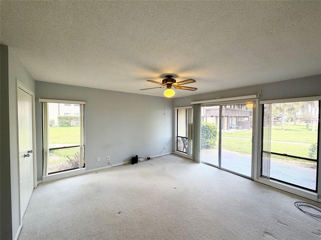 A bedroom features a wooden bed frame, matching dresser, blue bedding, and a ceiling fan — 56 CLUB HOUSE DRIVE UNIT 101, PALM COAST, FL