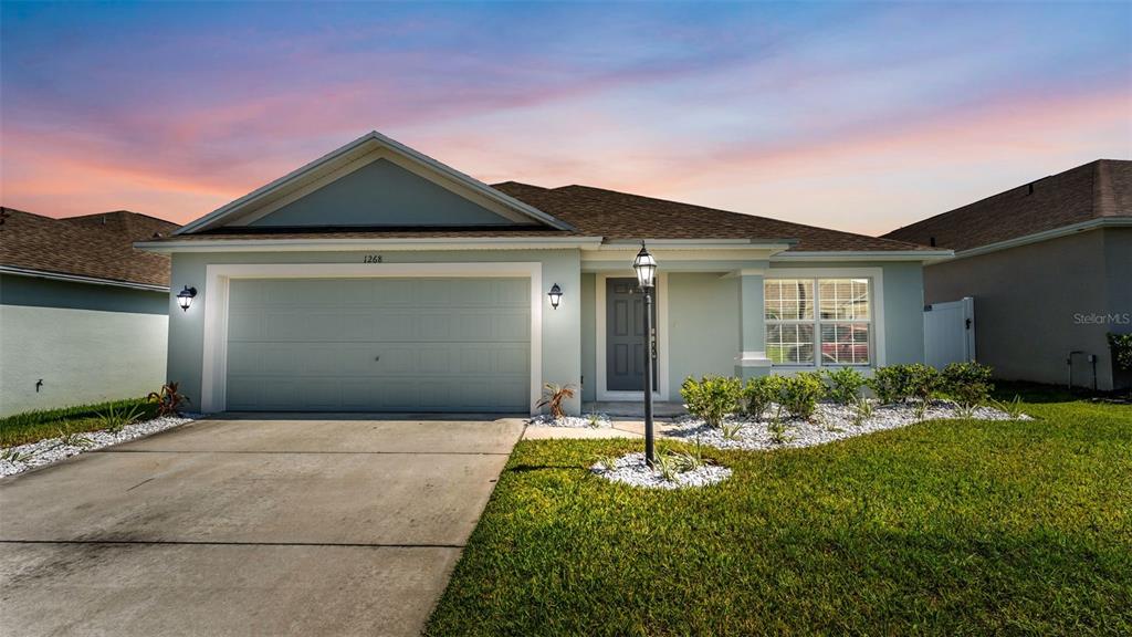 A single-story house with a light-colored exterior, a two-car garage, and a front lawn — 1268 PINTAIL PLACE, LAKELAND, FL
